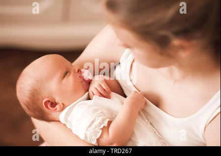 Piccolo bimbo sulle madri mani aspirando il succhietto closeup. Madre tenendo un neonato in camera. La maternità. La maternità. Vista dall'alto. Foto Stock