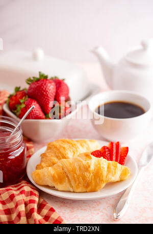 Tavolo per la prima colazione con croissant fragole e caffè Foto Stock