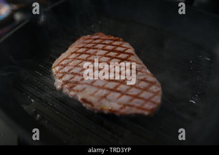 Lo chef arrosta carne al ristorante Foto Stock