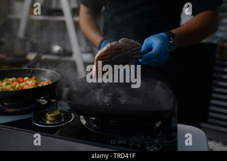 Lo chef arrosta carne al ristorante Foto Stock