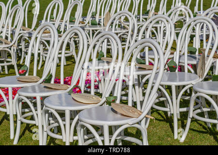 Configurazione di nozze - bianco con sedie in legno con viola e rosa di petali di fiori e paglia ventole per gli ospiti. Bali, Indonesia. Destinazione nozze tropicali, Bali. Foto Stock