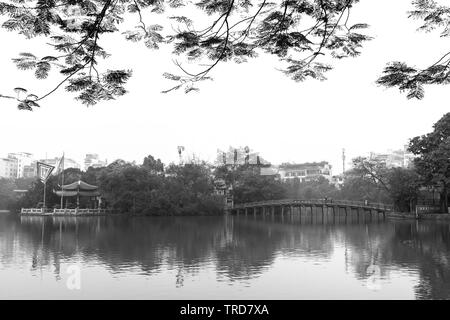 Architectural Huc Bridge profila agitare alberi lago con arcate rosso cultura di aragosta simboleggia la storia di migliaia di anni di Hanoi, Vietnam Foto Stock