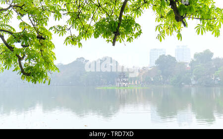 Albero in bud al lago Hoan Kiem nella capitale Hanoi, Vietnam con torre di tartaruga. Si tratta di una antica architettura conservata fino ad oggi Foto Stock