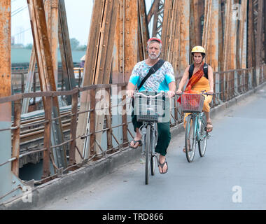 Le coppie di una bicicletta insieme sui binari della ferrovia che conduce su lunghe Bien bridge, progettato costruito da Gustave Eiffel ad Hanoi, Vietnam Foto Stock
