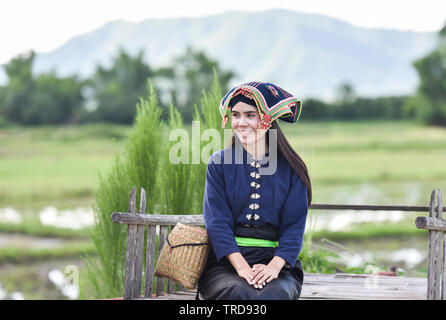 Donna asiatica di stile tailandese tribù vestito Tai Dam / Ritratto di giovane e bella ragazza sorridente Thailandia costume tradizionale che indossa con tessuto intessuto sulla testa di un Foto Stock