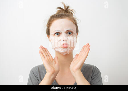 Giovane donna caucasica con stropicciato bianco maschera facciale sul suo viso Foto Stock