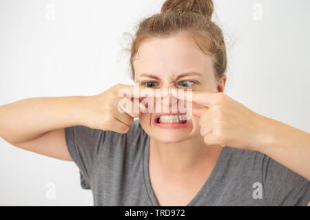 Giovane donna caucasica schiacciando un brufolo sul naso, funny espressione facciale Foto Stock