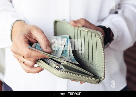 Stretta di mano di donna tenendo fuori di sterline dalla sua borsa Foto Stock