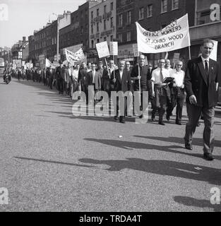 1960s, storici e impressionanti operatori postali della Royal Mail, membri dell'Unione degli operatori postali (UPW) che camminano in una processione attraverso il centro di Londra, tenendo striscioni con vari messaggi di protesta contro Ernest Bevin e chiedendo un accordo equo per i lavoratori postali. Foto Stock