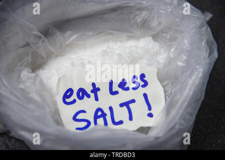 Mangiare meno sale per il concetto di salute / mucchio di sale in un sacchetto di plastica sullo sfondo Foto Stock
