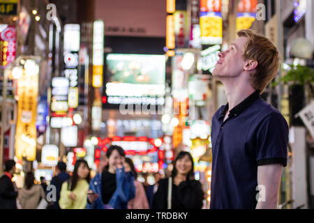 Una bella bionda per turisti in cerca di al lato di un neon di Tokyo street Foto Stock
