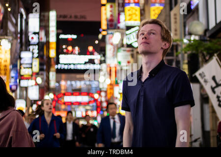 Una bella bionda per turisti in cerca di al lato di un neon di Tokyo street Foto Stock