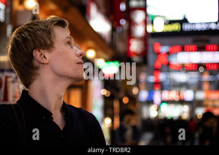 Una bella bionda per turisti in cerca di al lato di un neon di Tokyo street Foto Stock