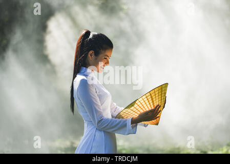 Asia donna vietnam o in stile cinese vestito / Ritratto di giovane e bella ragazza vietnamita costume tradizionale che indossa con hat foglia di tessitura a mano su n Foto Stock