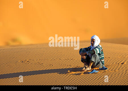 Berber seduta nella sabbia del deserto, Marocco, Merzouga Erg Chebbi Foto Stock