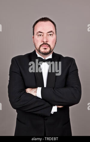 Ritratto di un elegante uomo vestito di una cena sollevato con bracci incrociati cercando arrogante Foto Stock