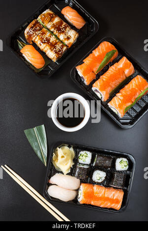 Vari tipi di sushi servita su sfondo nero. Vista superiore Foto Stock