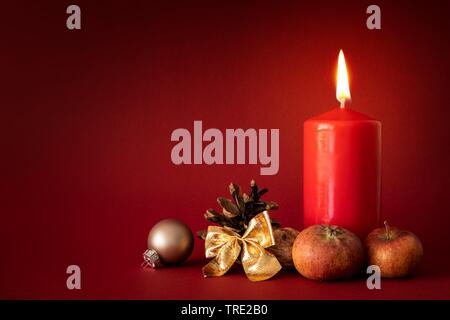 Avvento Decorazione con candela che brucia su sfondo rosso Foto Stock