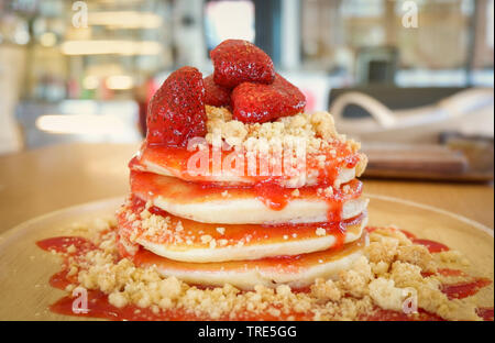 Frittelle di frutta fragola e salsa su sfondo di legno nella torta di caffè e coffee shop Foto Stock