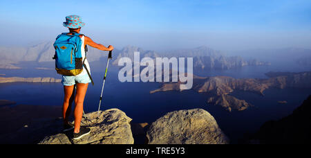 Femmina wanderer godendo la vista da una montagna alta alla Baia di Sham, Oman, Khasab Foto Stock