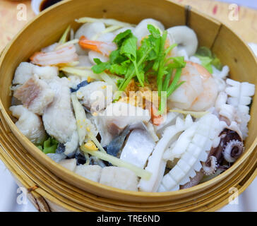 Pesce al vapore con pesce calamari gamberetto boreale sul sistema di cottura a vapore in legno Foto Stock