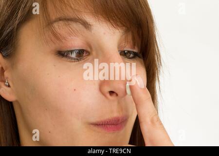 Giovani donne simpatica tenendo il suo dito con crema per il viso nella parte anteriore del naso Foto Stock