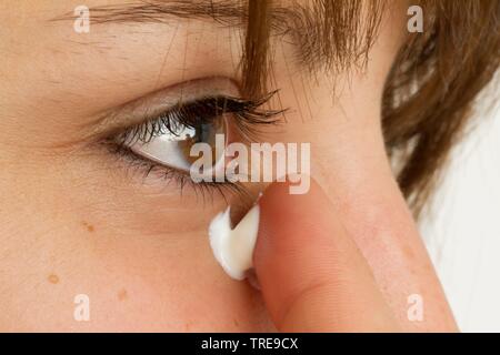 Giovani donne simpatica tenendo il suo dito con crema per il viso per la sua pelle Foto Stock