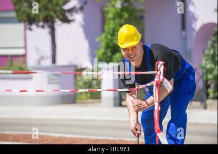 Operaio edile, installando una barriere con nastro di avvertenza Foto Stock