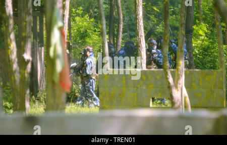 Battaglia di paintball. Lo scontro tra squadre avversarie è in pieno svolgimento: tutti i giocatori punto le loro armi presso i propri avversari per sparare proiettili di vernice. Foto Stock