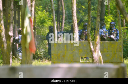 Battaglia di paintball. Lo scontro tra squadre avversarie è in pieno svolgimento: tutti i giocatori punto le loro armi presso i propri avversari per sparare proiettili di vernice. Foto Stock