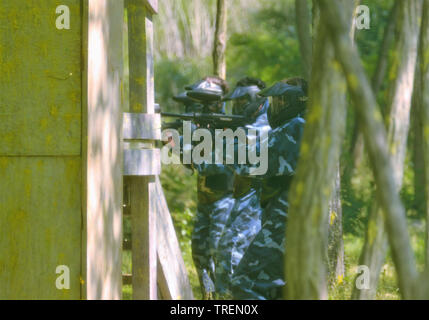 Battaglia di paintball. Lo scontro tra squadre avversarie è in pieno svolgimento: tutti i giocatori punto le loro armi presso i propri avversari per sparare proiettili di vernice. Foto Stock