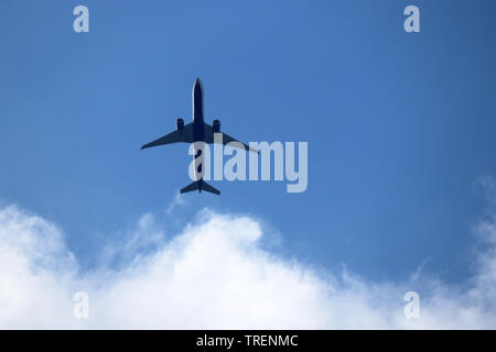 In aereo nel cielo blu con nuvole bianche. Piano commerciale in un volo in prossimità fino, vista dal basso Foto Stock