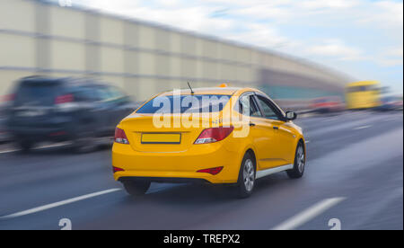 Taxi giallo si muove sulla strada di città Foto Stock