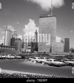 1960s, storico, Chicago, e attraverso un parcheggio di automobili americane, una vista della città che mostra i grattacieli e blocchi di uffici, uno è quello della compagnia di assicurazione americana, Prudential. Foto Stock