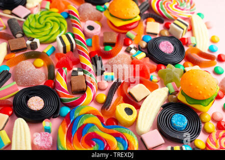 Caramelle con gelatina colorata serie di diversi bambini dolci e delizie su rosa come sfondo di festa Foto Stock