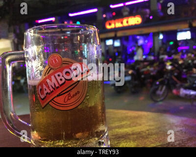 Close-up di un vetro della Cambogia birra al pub Street con un nightclub sfocata background in Siem Reap Cambogia, di notte. Foto Stock
