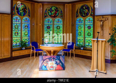 Dipinto dell'Ultima Cena accanto all altare in un piccolo Romano cappella cattolica ornato di vetrate dietro. Foto Stock