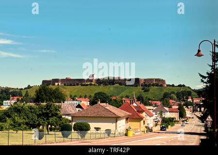 Vista da lontano della Fortezza vecchia di Bitche, Francia da un colorato strada residenziale con l'azzurro del cielo. Foto Stock