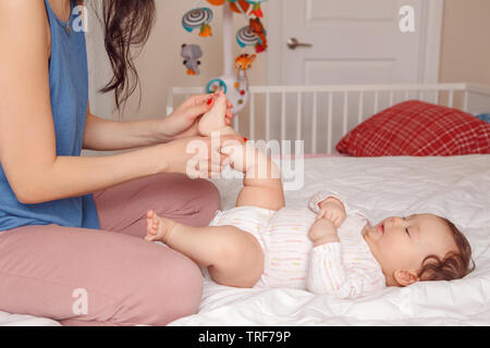 Ritratto di carino adorabile razza mista Asian madre con bambino neonato facendo massaggi ed esercizi fisici. Inizio dello sviluppo e della sanità dello stile di vita Foto Stock