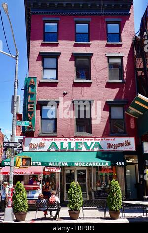 Giovane seduto sul banco in Little Italy strada fuori Alleva casearia italiana al Grand e strade di gelso, Manhattan, New York, NY Foto Stock