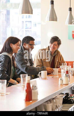 Clienti felici gruppo multietnico di persone amici avente caffè insieme al contatore in informale cafe diner ristorante Foto Stock