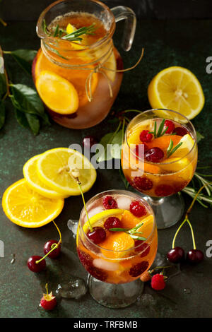 Fatti in casa vino rinfrescante sangria o punzone con frutti. La sangria cocktail con frutta fresca e bacche e rosmarino sul buio di una pietra o ardesia sfondo. Foto Stock