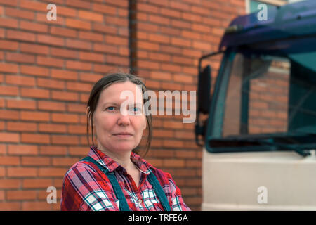 L'agricoltore femmina e per impieghi medi farm carrello. Ritratto di bella adulto donna caucasica indossando plaid shirt e jeans denim tute da bib guardando è venuto Foto Stock