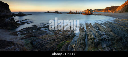 Panorama di Playa de Gueirua costa rocciosa con scogliere in background al tramonto, Asturias, Spagna Foto Stock