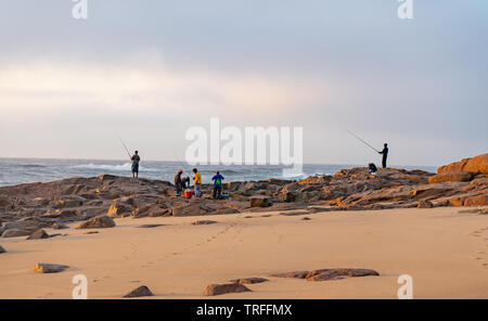 Fisherman sulle rocce al mattino presto sun. Durban, Costa Orientale, Sud Africa Foto Stock