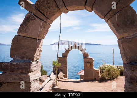 Vista generale di Isola Amantani, visto da di Taquile Island con tradizionale Taquile archi in primo piano, il lago Titicaca Puno, Regione, Perù Foto Stock