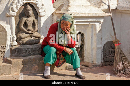 Manutenzione femmina lavoratore adagiata vicino statue a Swayambhunath tempio buddista, Kathmandu, Valle di Kathmandu, Nepal Foto Stock