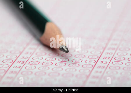 Scuola gli studenti le mani per il sostenimento degli esami, la scrittura di esame tenendo premuto matita su modulo ottico di test standardizzati con foglio per le risposte facendo esame finale in cla Foto Stock