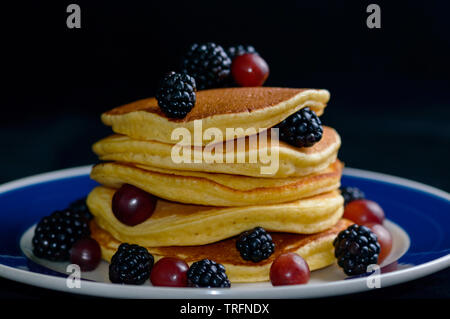 Impilati pancake con frutta estiva, isolato su nero. Foto Stock