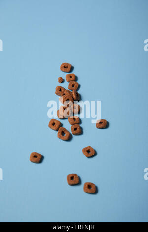 Croccante di kitty cibo sparsi lungo un sfondo blu Foto Stock